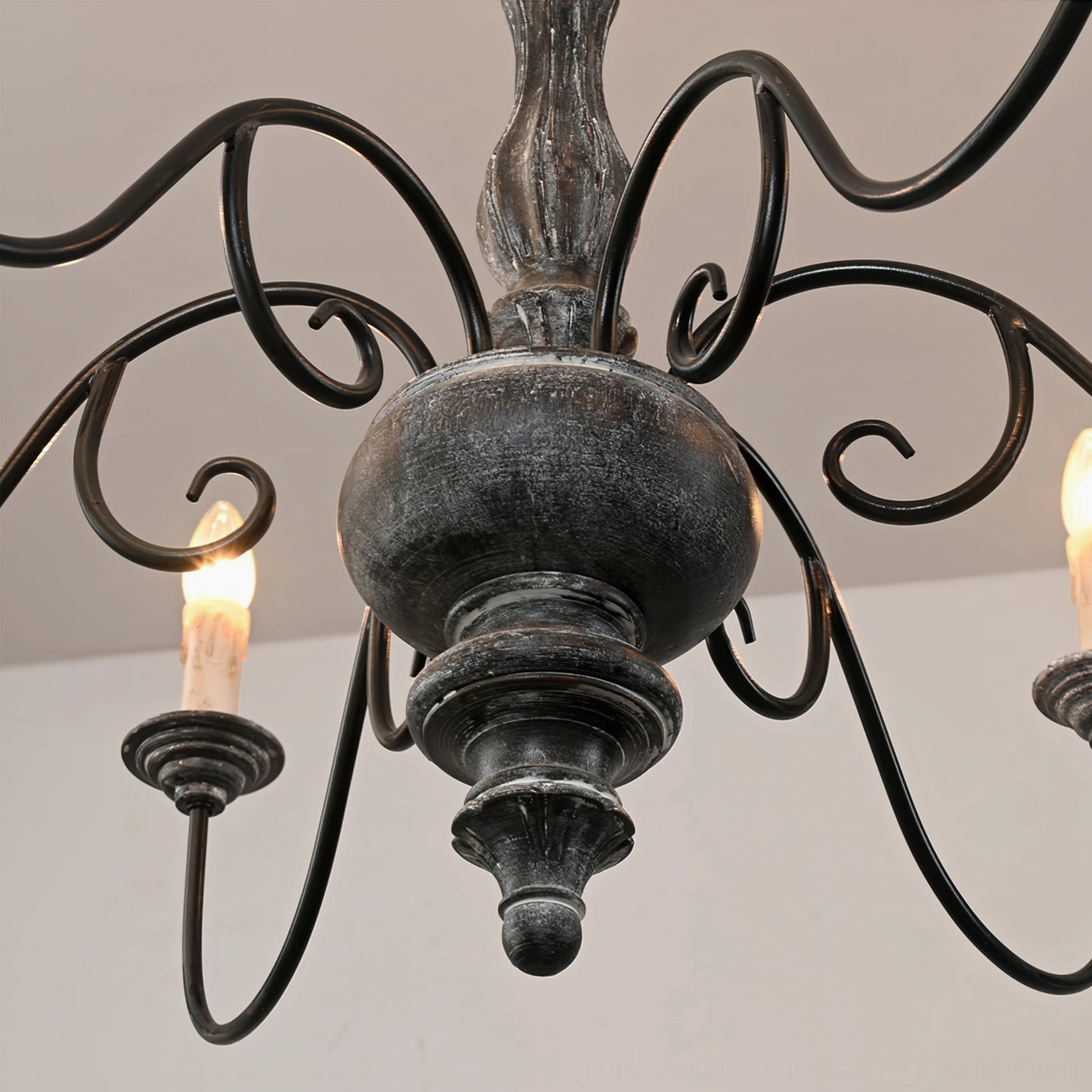 Close-up detail of anchor chandelier distressed black iron arms and carved wooden center rustic design