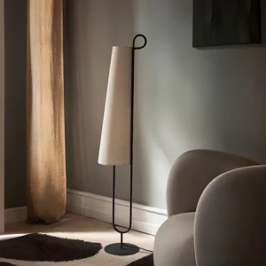 Modern Ancora floor lamp in living room corner with grey armchair and neutral home decor, warm ambient lighting