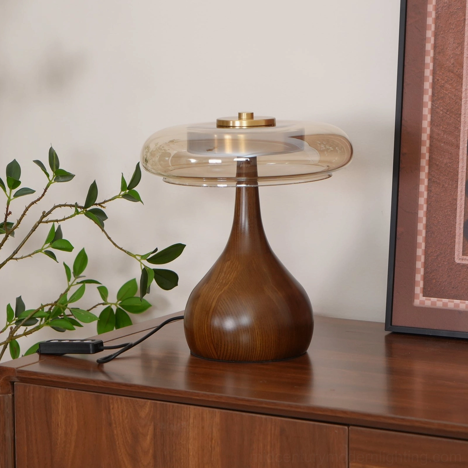 Mid-century modern Andi table lamp on dark wood dresser with green foliage and wall art