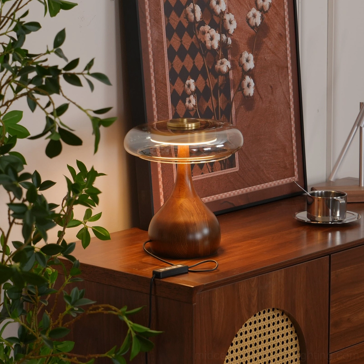 Andi table lamp on wooden dresser with woven cabinet details, metal tea set, and plants