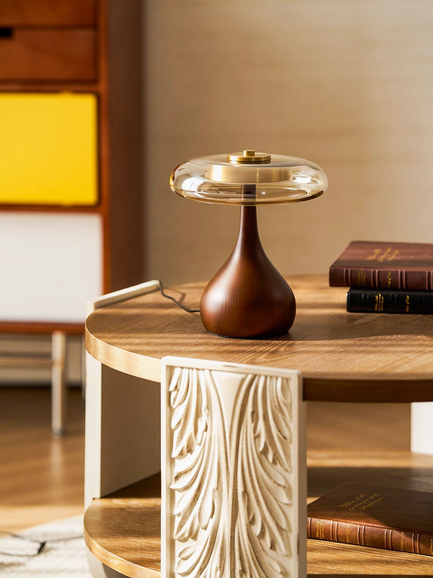 Andi Glass Table Lamp walnut finish on carved wooden side table with yellow cabinet backdrop