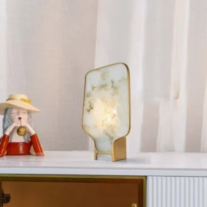Andrea alabaster table lamp illuminated on white dresser with sheer curtain backdrop, modern luxury bedroom styling