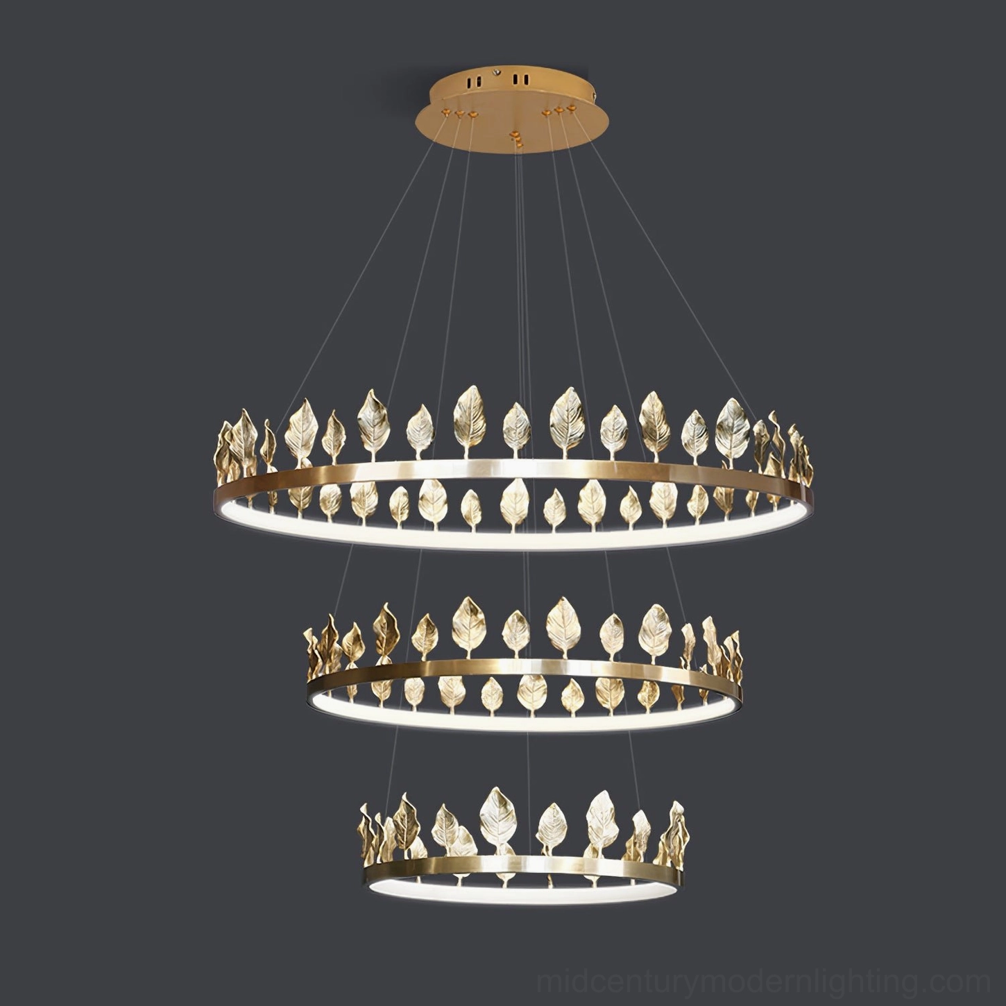 Stacked view of three-tier Anello brass leaf chandeliers with nested ring design on dark background