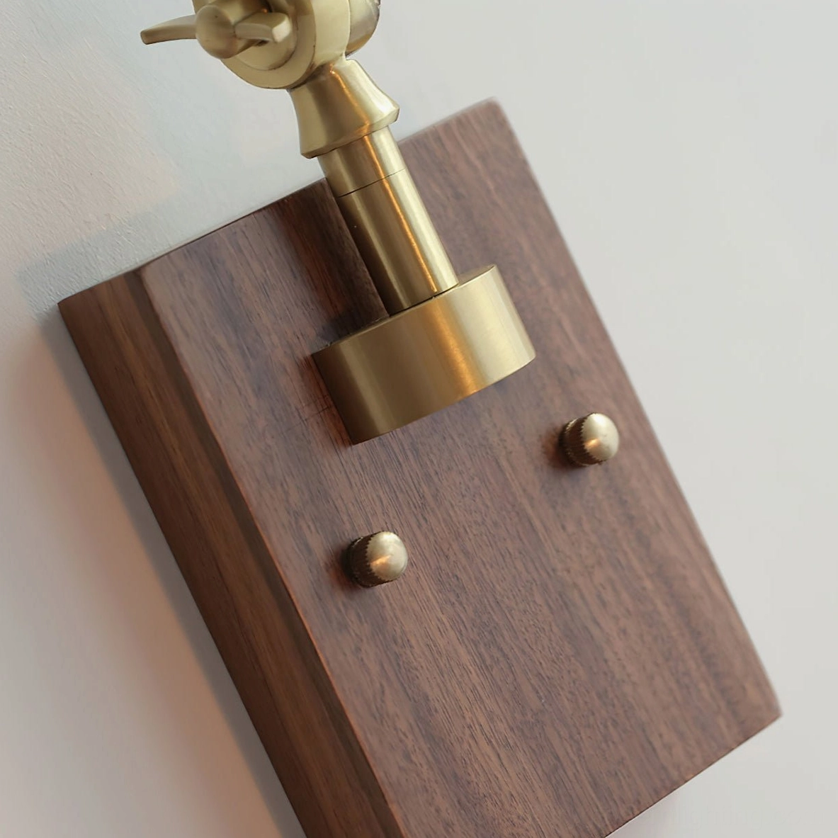 Angeline wall lamp walnut wood mounting plate with brass fittings, close-up detail of wall mount base and adjustment knobs