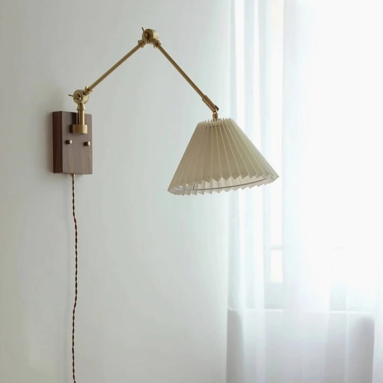 Angeline swing arm wall lamp front view in interior room, pleated fabric shade with brass and walnut hardware, ambient lighting