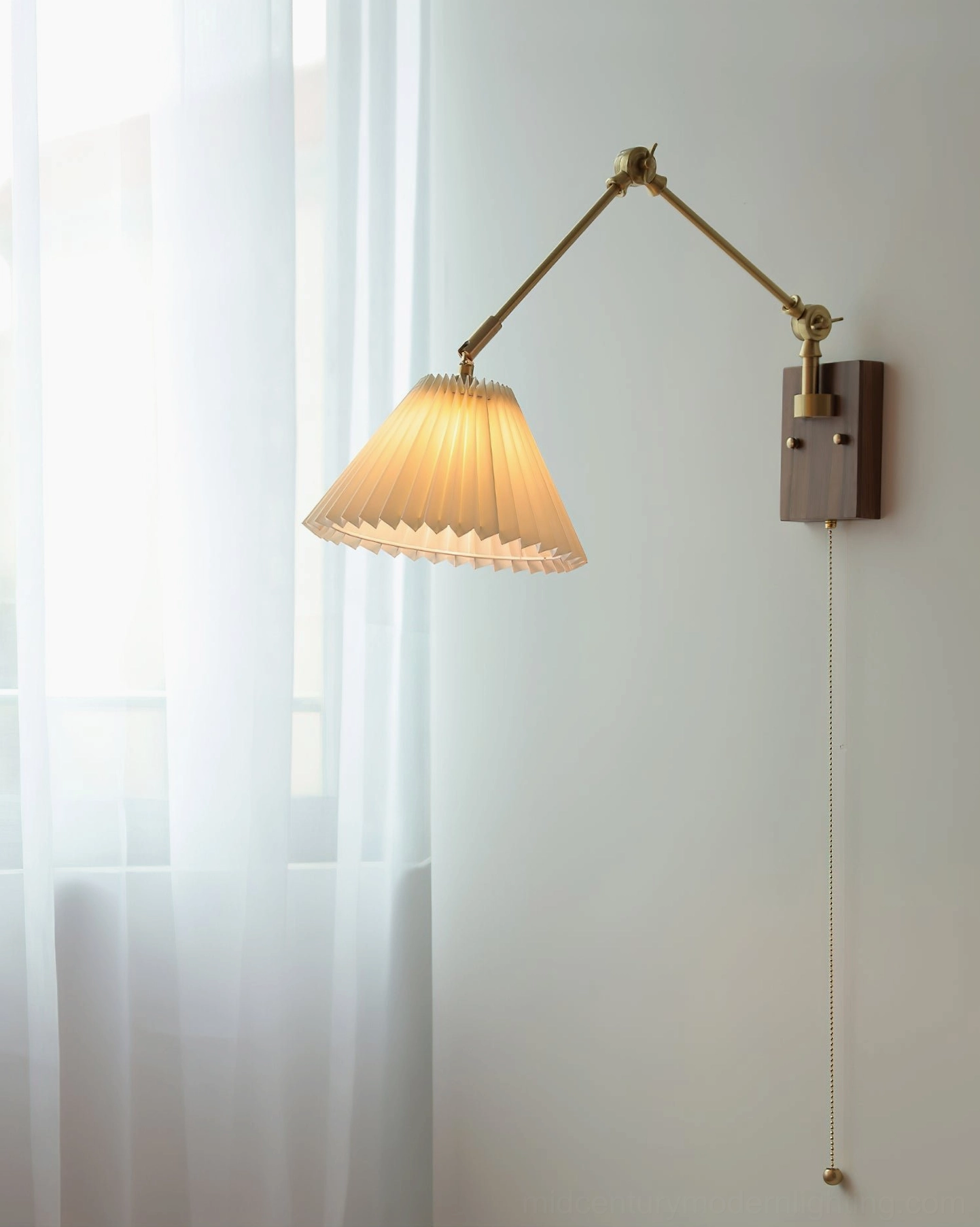 Angeline swing arm wall lamp detail shot showing slim pull chain with brass bottom pendant finial and elegant articulation mechanism in indoor setting