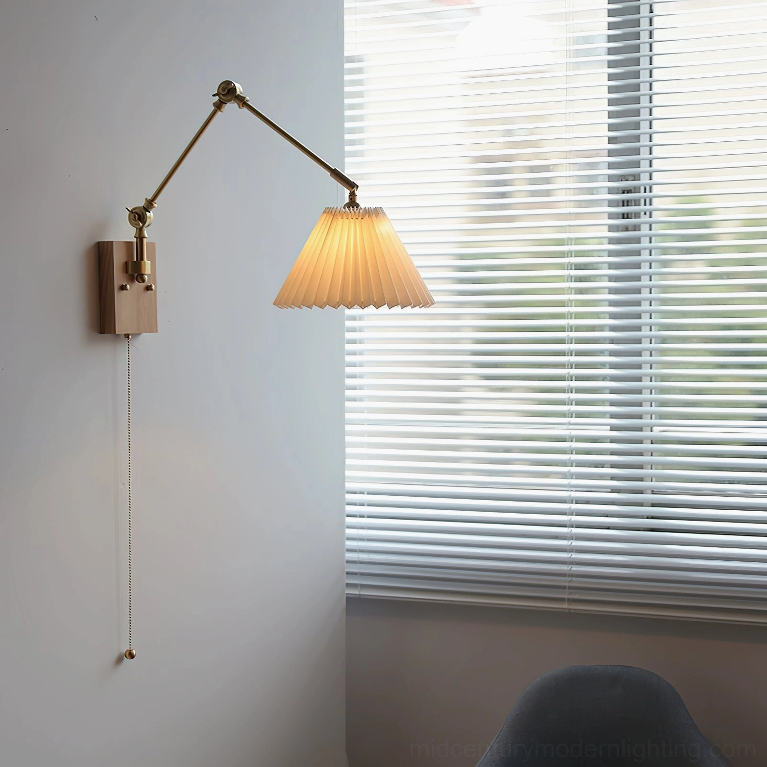 Angeline swing arm wall lamp installed in minimalist study room with louvered window, demonstrating warm lighting and three-quarter perspective with zipper pull cord switch