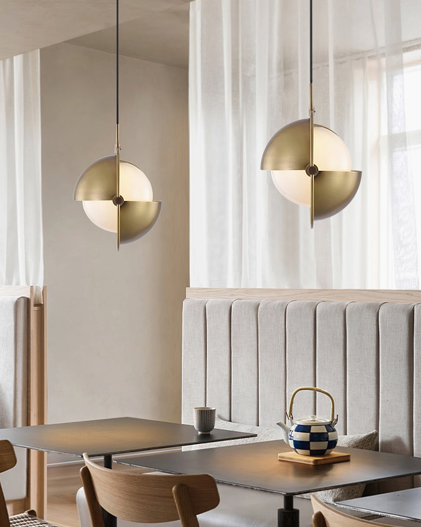 Pair of brass Anix pendant lights in cafe-style dining booth with natural window light ambiance