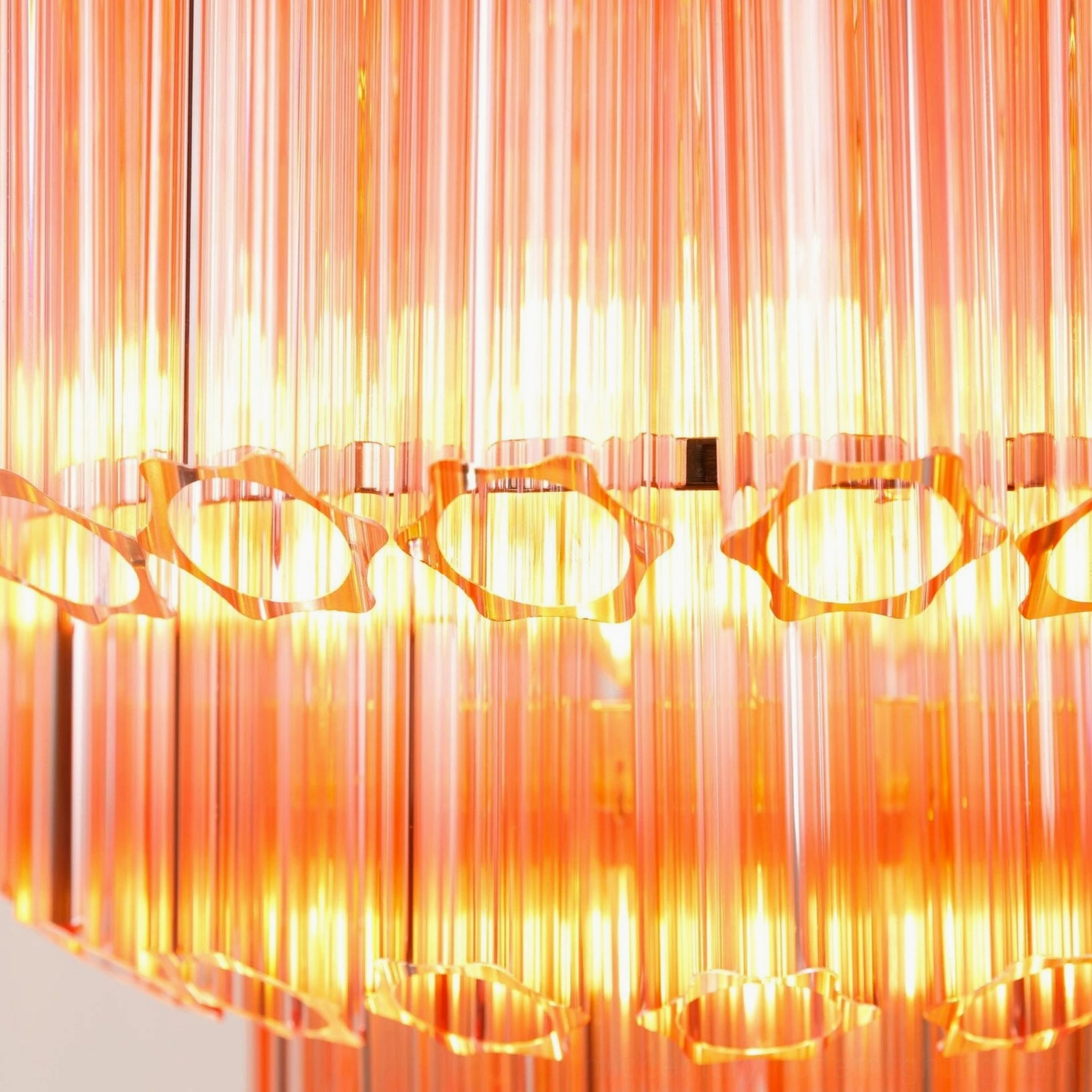 Antella Sunburst Chandelier close-up detail - warm glowing pink translucent Murano glass panels with precision cutwork lighting effects