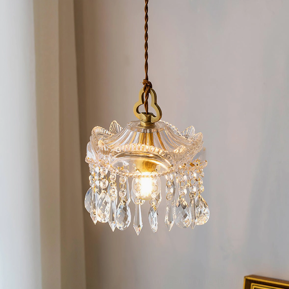 Vintage brass crystal pendant chandelier hanging from twisted cord with tassel crystal accents, interior corner view