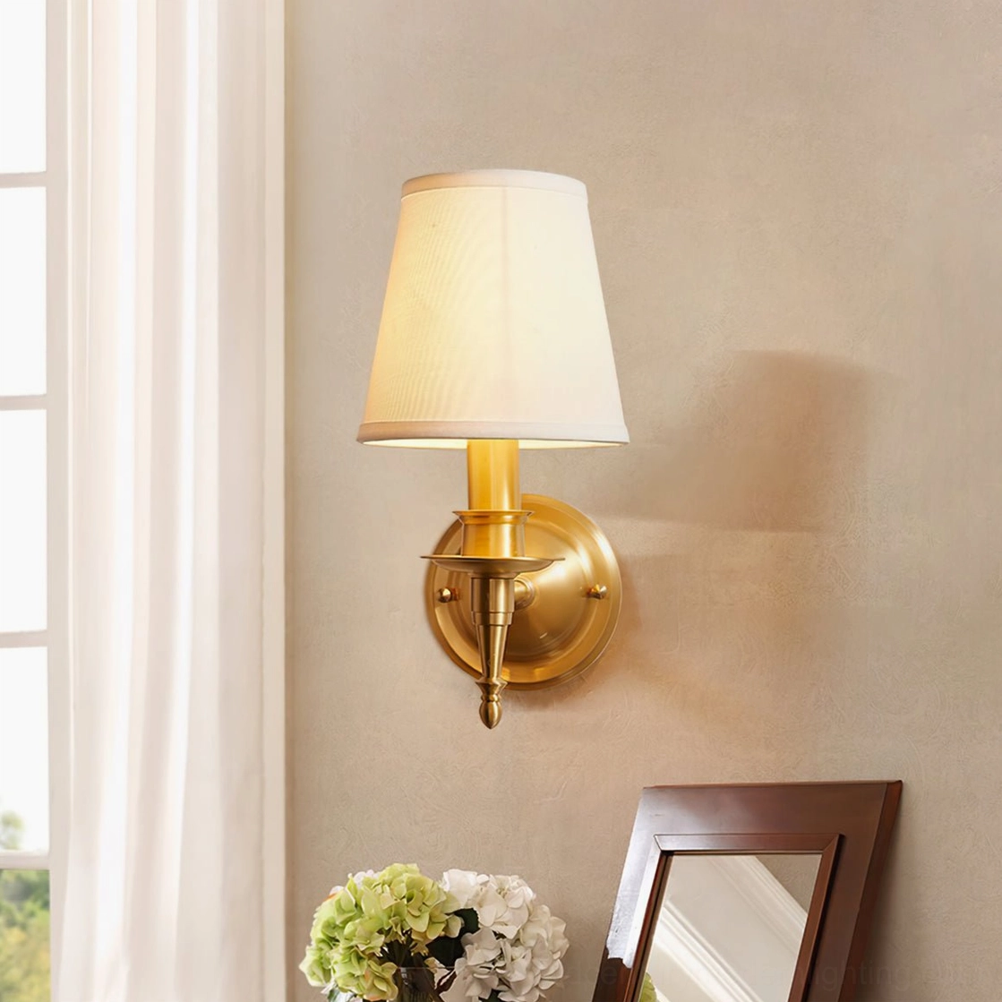 Antique brass wall sconce installed in bedroom interior with neutral wall decor and window