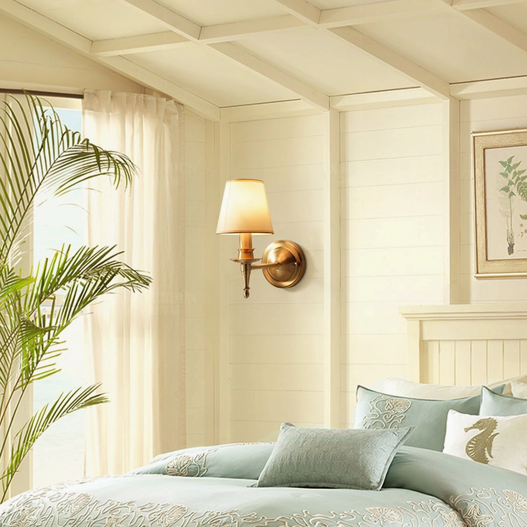 Antique brass sconce mounted in bedroom bedside setting with green linens and warm ambient lighting