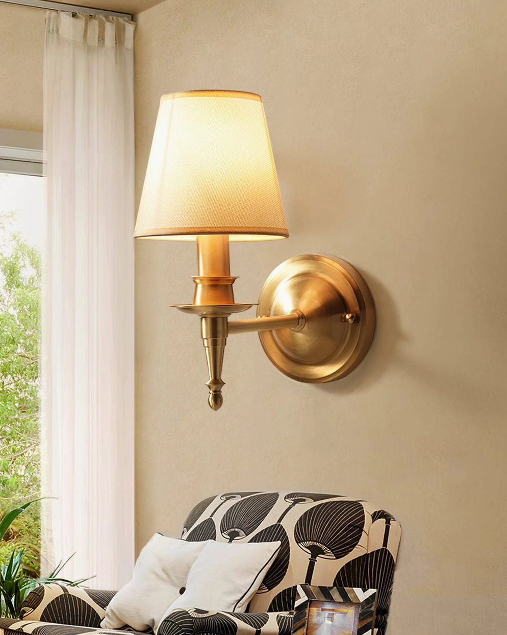 Antique brass wall sconce in living room setting with patterned sofa and ambient lighting