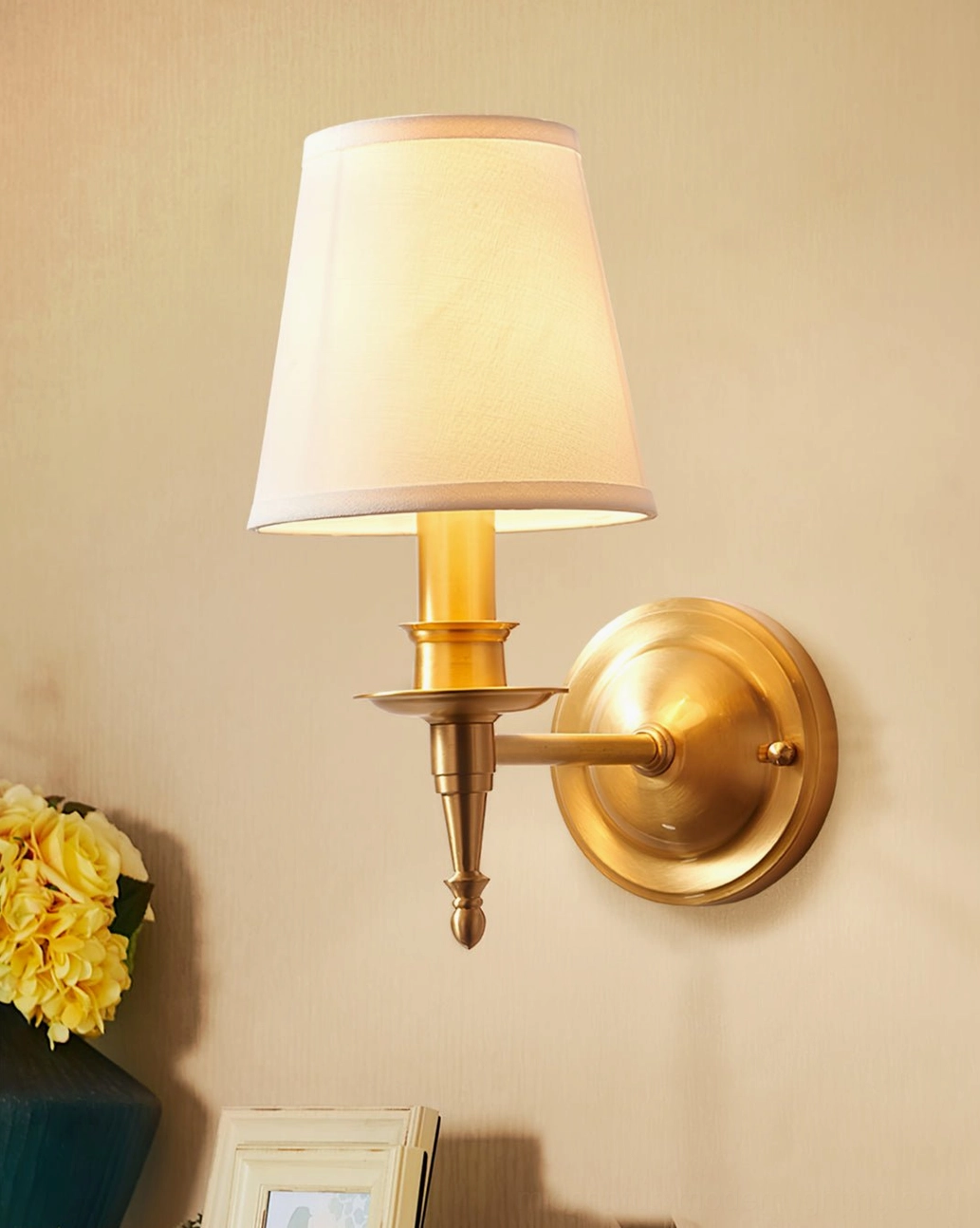 Antique brass wall sconce mounted on interior wall showing warm color temperature and linen glow