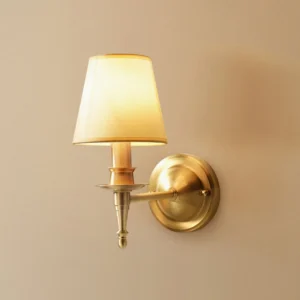 Close-up side view of antique brass wall sconce highlighting brass arm articulation and linen diffuser detail