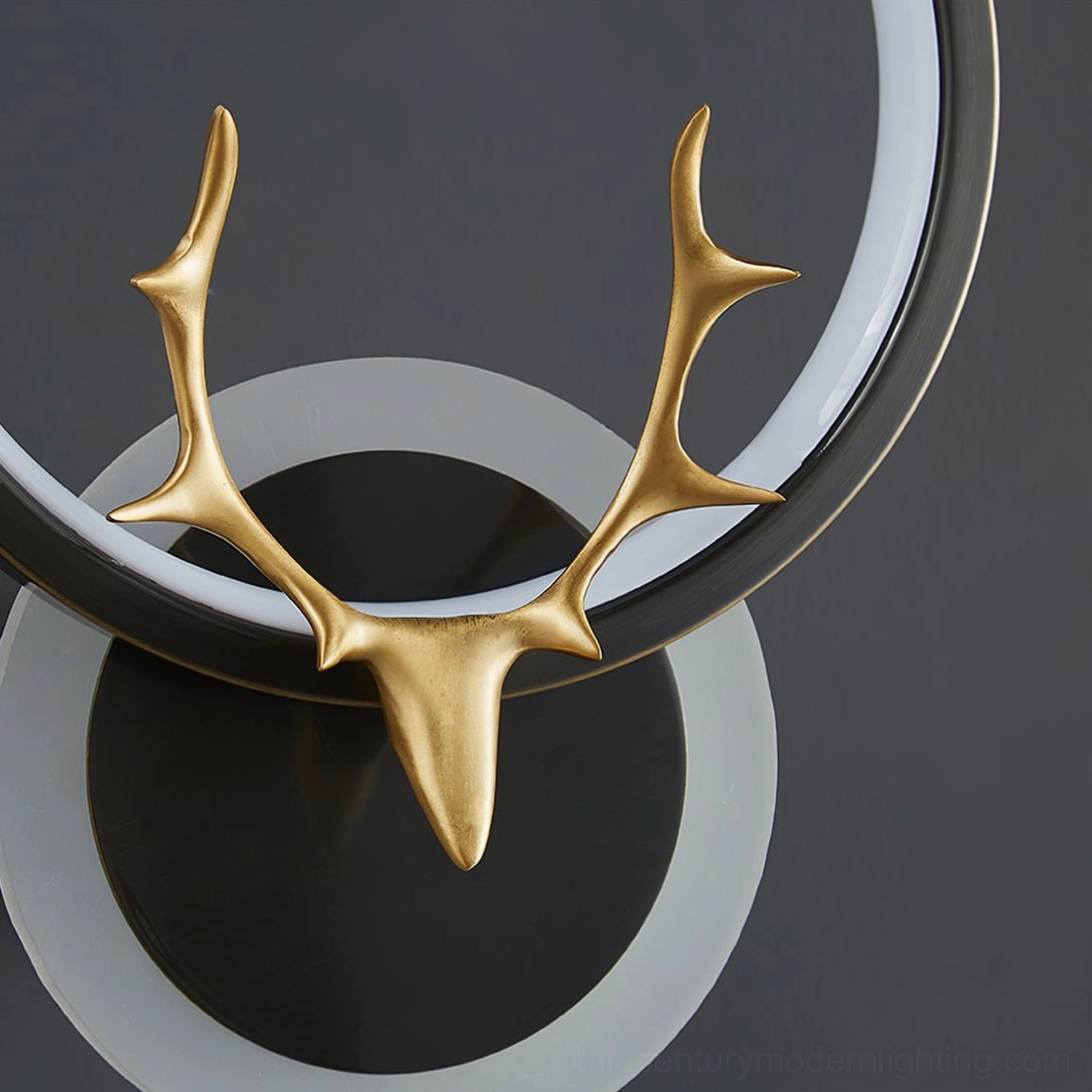 Close-up detail of antler wall lamp top section showing deer antler, black-white ring frame and metal base