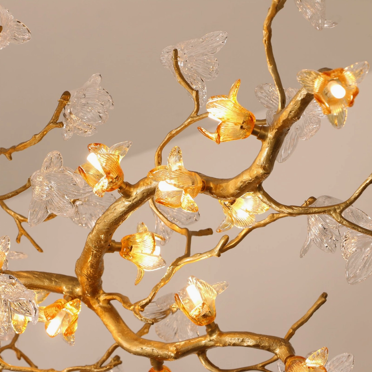 Close-up macro detail of Aosta chandelier brass branch and amber glass flower with G9 socket lighting