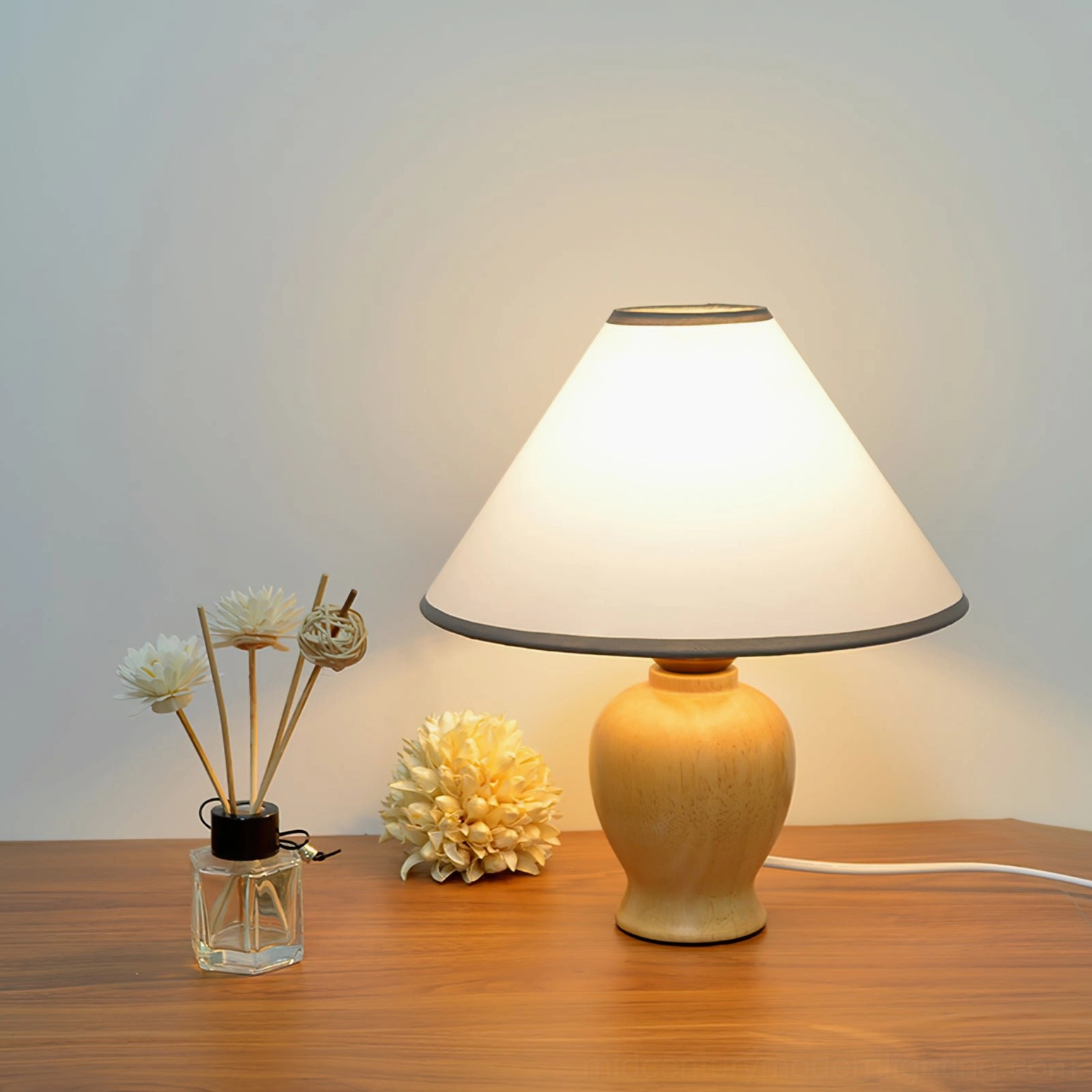 Arbol wooden table lamp on desk with reed diffuser and dried florals, warm ambient glow lighting three-quarter composition