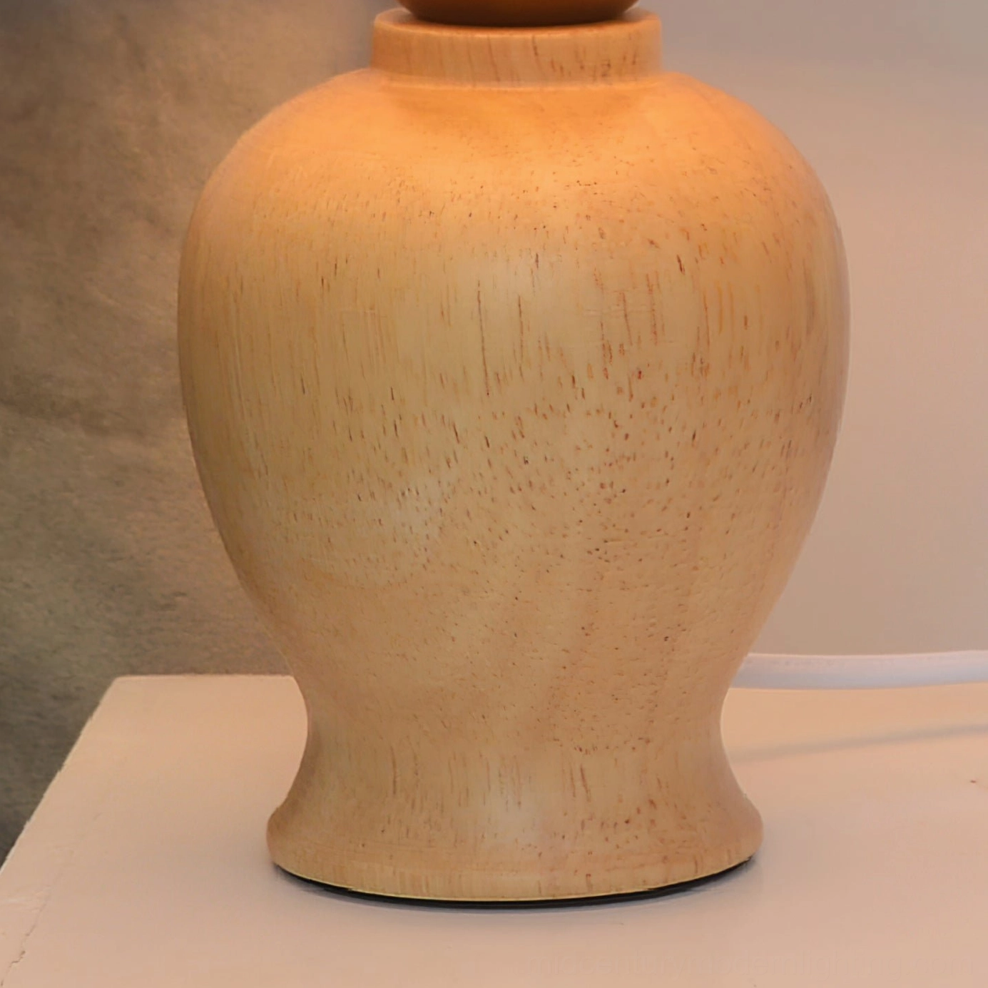 Close-up overhead view of Arbol lamp base on white surface, polished natural solid wood texture revealing authentic grain patterns