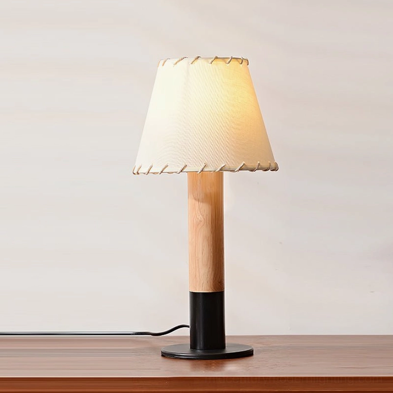 Black metal arbor table lamp with warm-glowing fabric shade on wooden console table