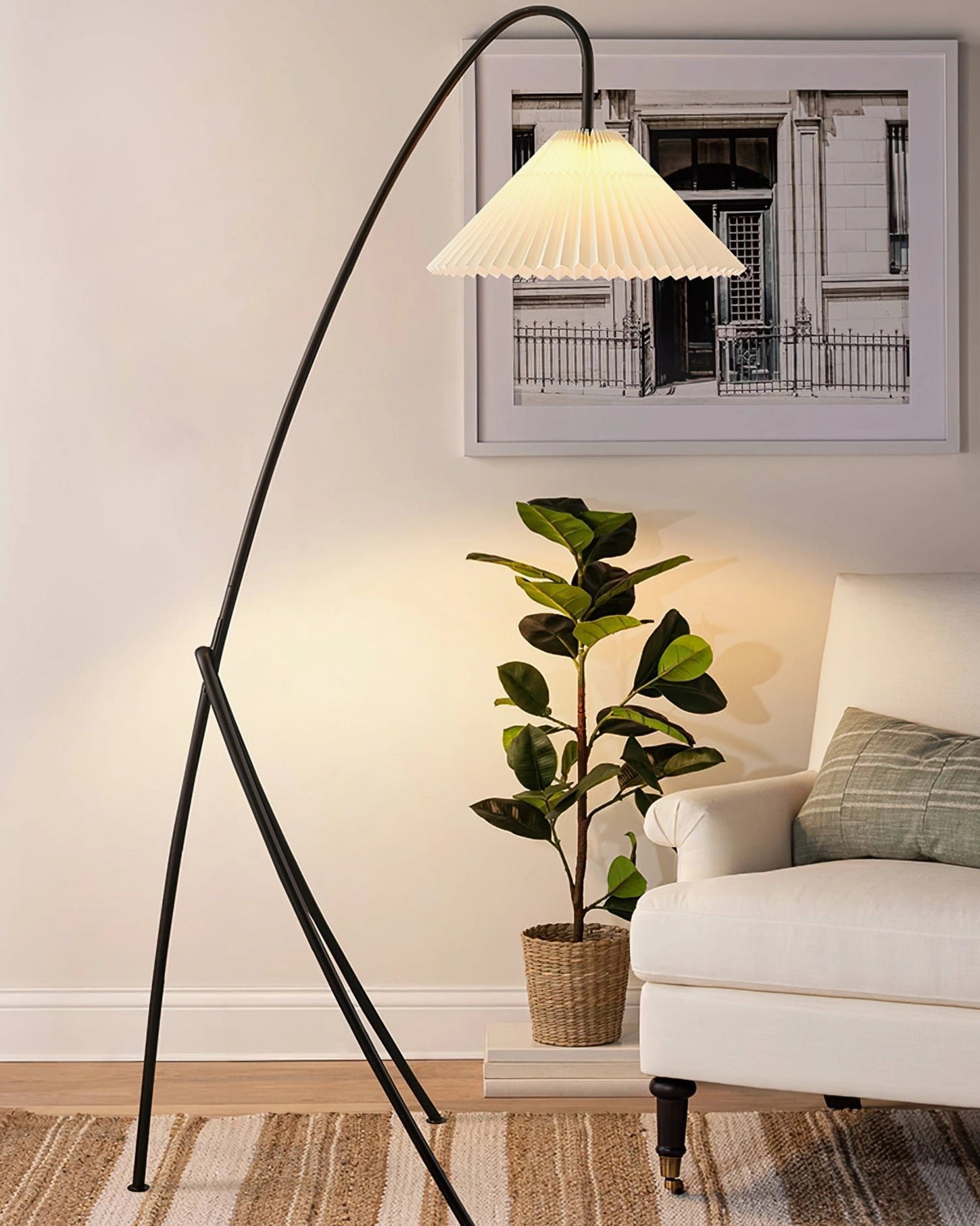 Minimalist arc tripod floor lamp in cozy residential living room, side angle shot demonstrating soft modern home decor aesthetic