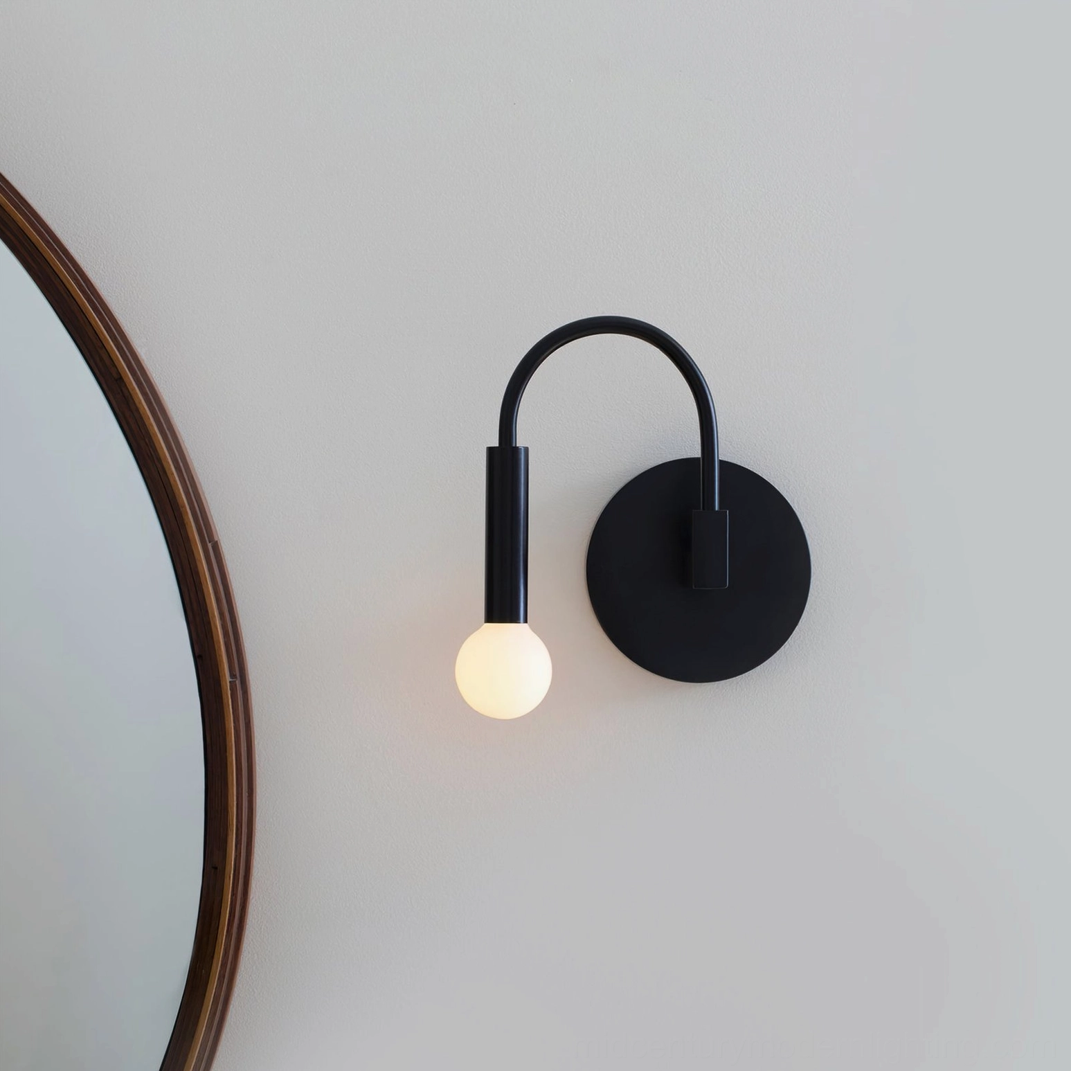 Arch wall lamp installed beside round mirror on white wall, contemporary bedroom setting