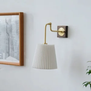Argon mid-century modern wall lamp three-quarter view showing pleated shade and curved brass arm against home wall with framed artwork