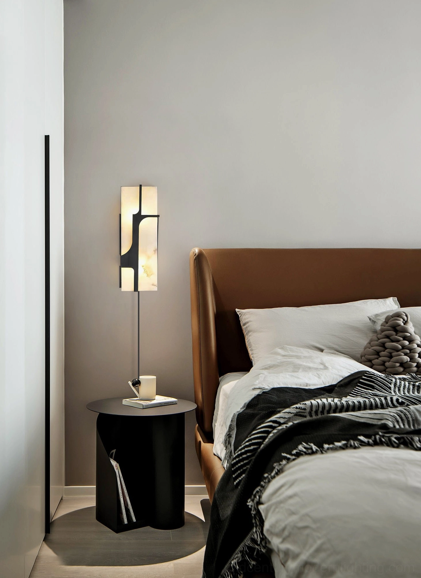 Ariel alabaster plug-in wall sconce in contemporary minimalist bedroom with black cylindrical nightstand