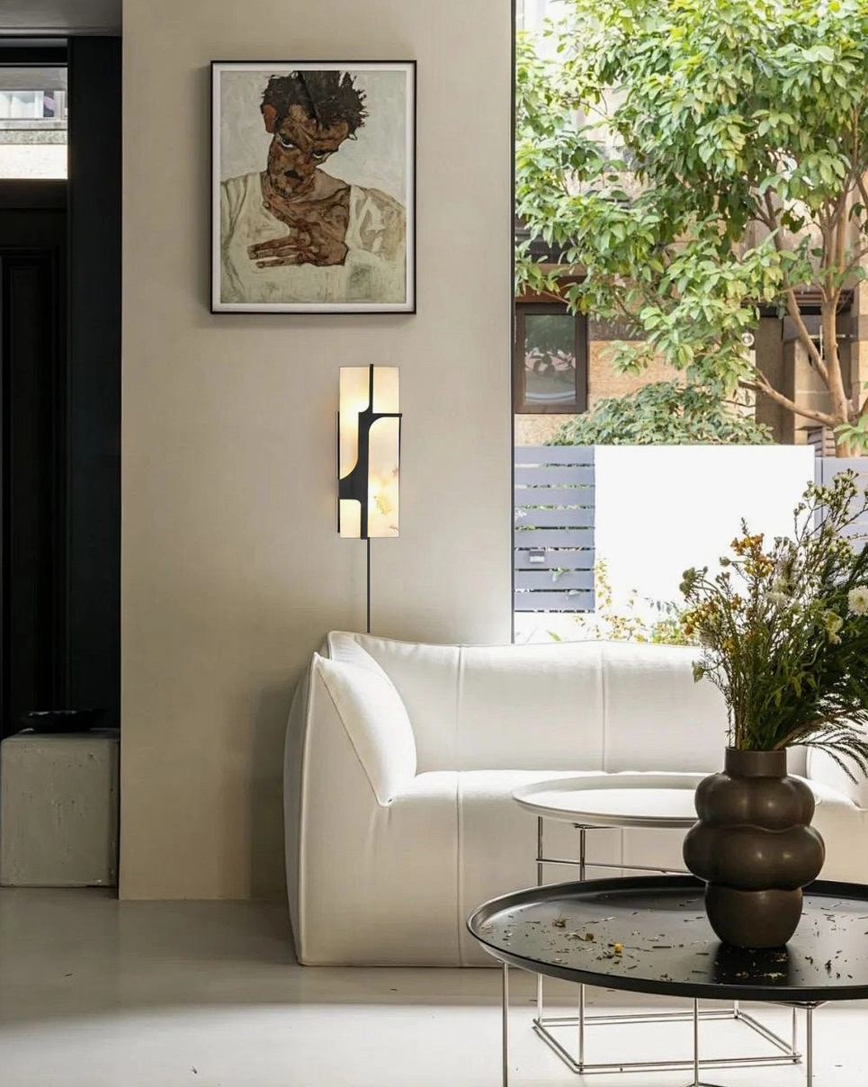 Ariel alabaster wall sconce as accent lighting in modern minimalist living room with white sofa and artwork