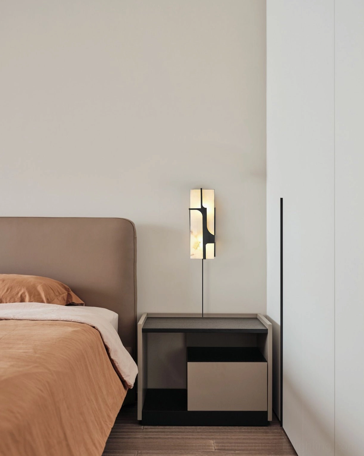Ariel alabaster plug-in sconce providing ambient lighting in minimalist compact bedroom with contemporary design