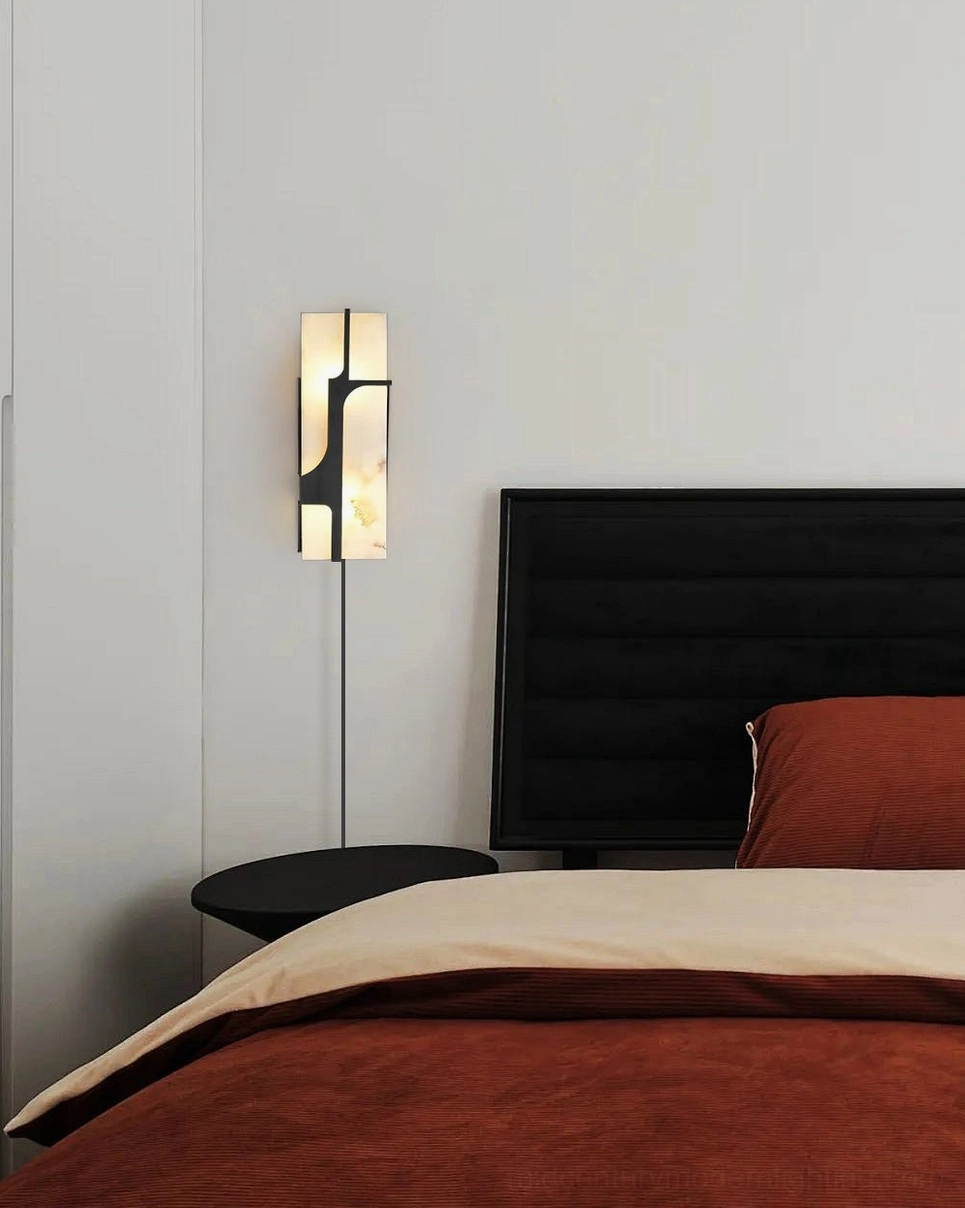 Ariel black and white alabaster wall sconce bedside lamp next to black tufted headboard