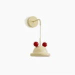 Aries whimsical wall lamp in cream and red with smooth dome shade and bold spherical accents, front view on white studio background
