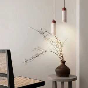 Pair of Arlene travertine pendant lights installed in minimalist living room with rattan furniture and neutral decor