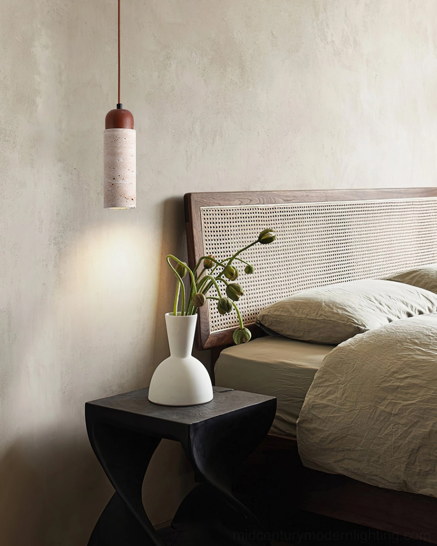 Single Arlene travertine cylinder pendant lamp hanging in rustic bedroom with rattan headboard