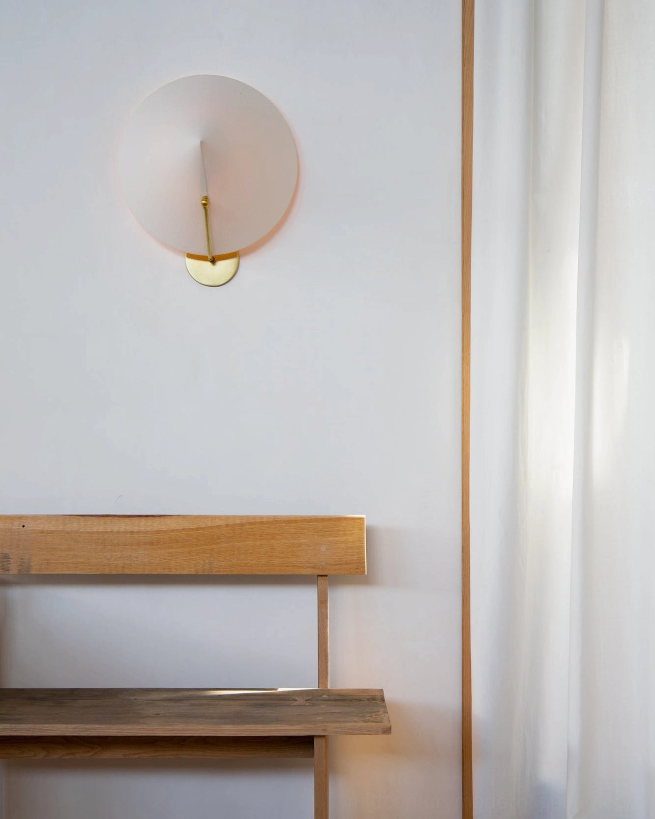 Arno flat round frosted glass wall sconce with brass gold hardware in modern home entryway