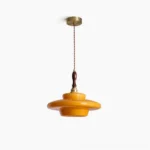 Aroma mid-century modern pendant lamp with layered amber glass shade and brass hardware in studio lighting