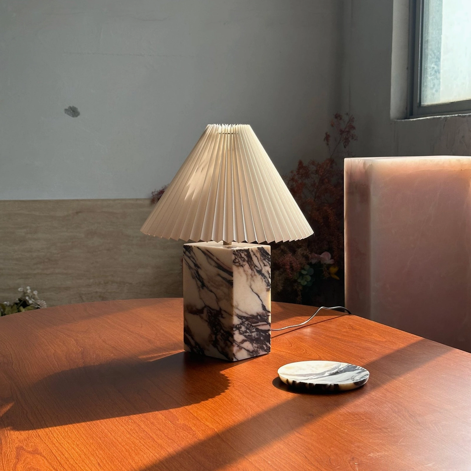 Arouca marble table lamp by window on wooden table showcasing natural stone veining and pleated shade