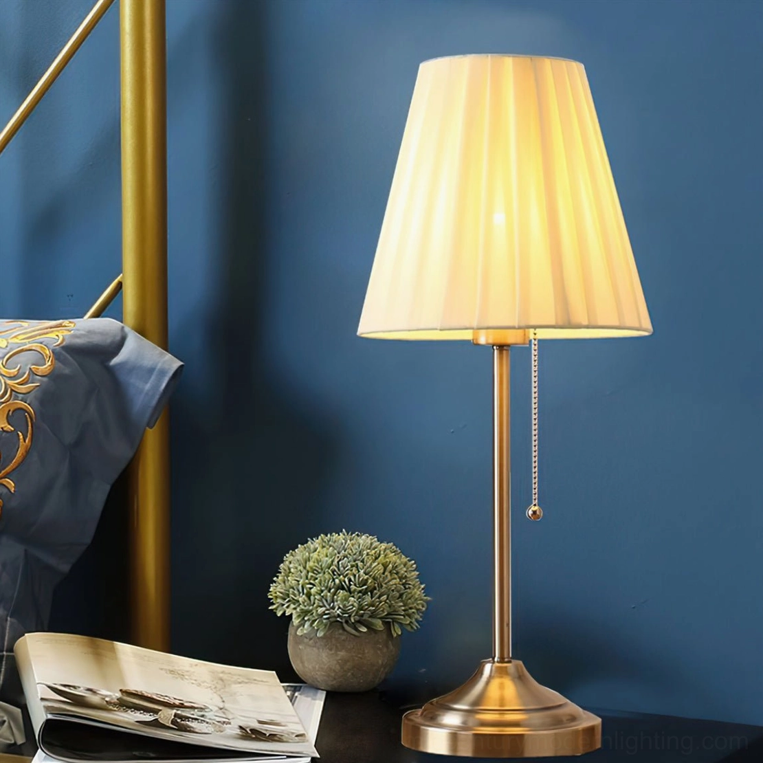 Arstid brass gold table lamp illuminated at night on bedroom bedside with books and floral decor