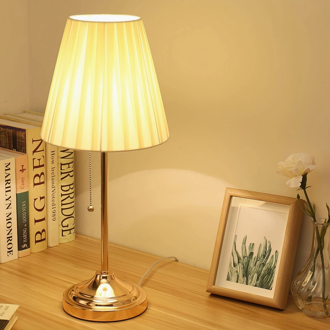 Arstid gold metal base table lamp with warm finish on living room side table with decorative objects
