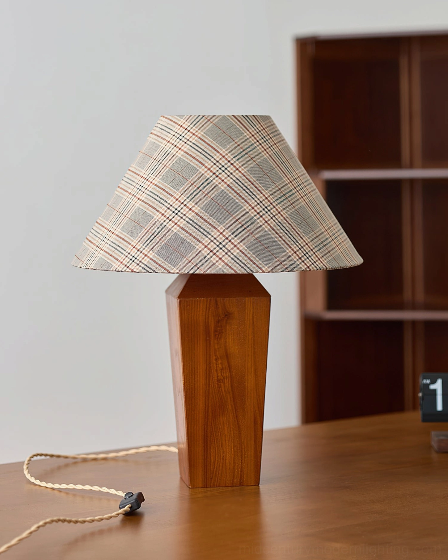 Fully assembled cabin table lamp on desk with wooden bookshelf backdrop, geometric walnut base detail
