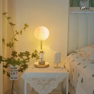 Astronaut moon lamp in bedroom bedside setting with warm ambient light illuminating green plant and cozy interior design