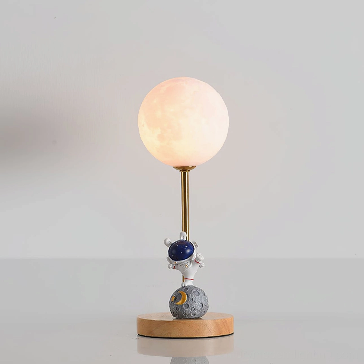 Close-up front view of astronaut moon table lamp showing blue astronaut helmet and crater-textured moon base on studio background