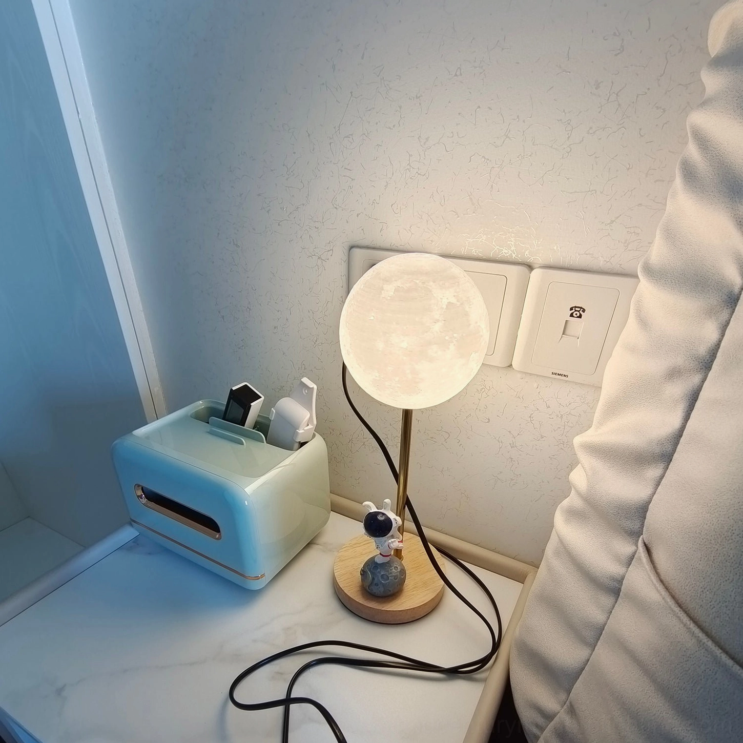 Astronaut moon lamp demonstrating interior design pairing with warm wood furniture and metallic gold accents