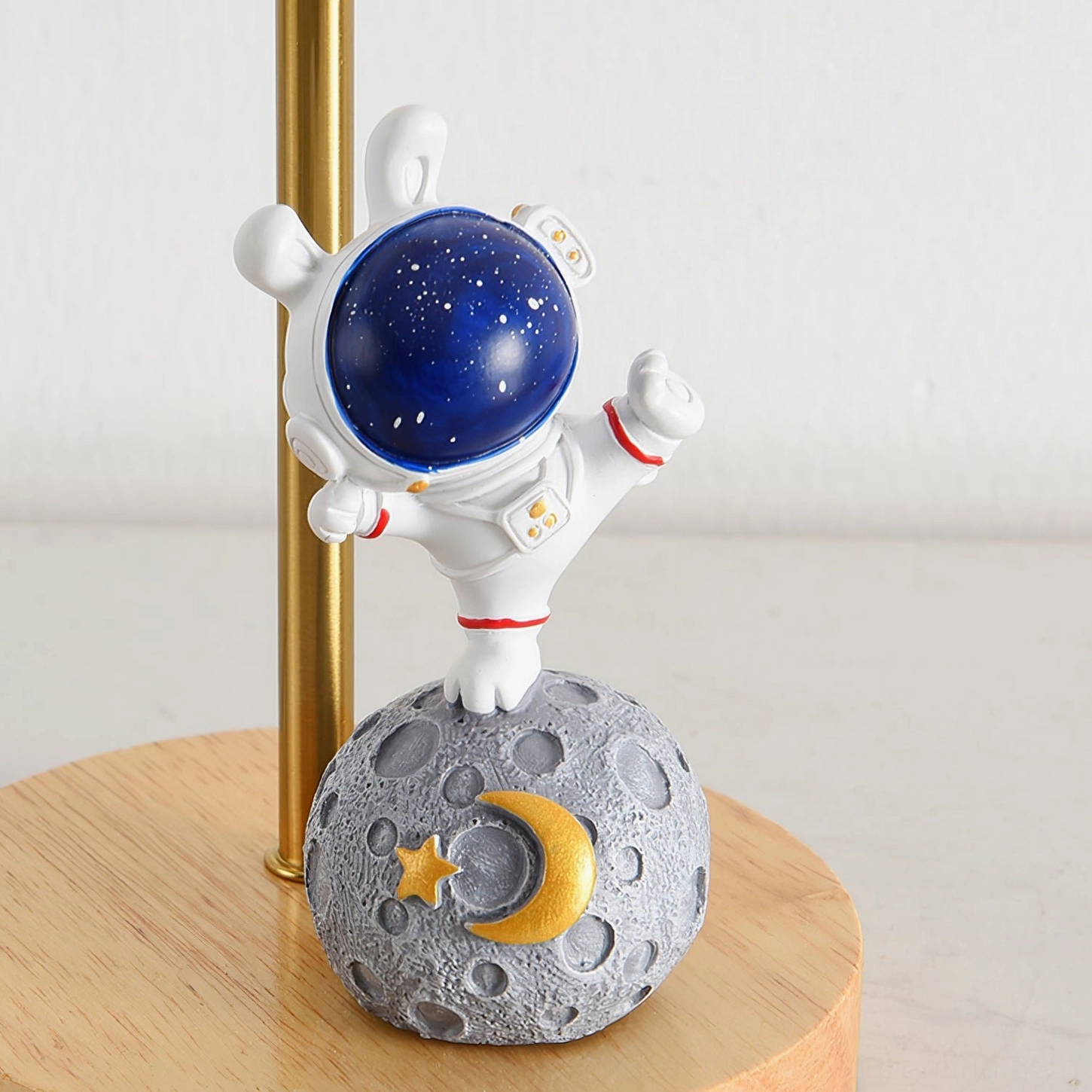 Front close-up detail of astronaut moon lamp showing raised-arm astronaut figurine design with crater texture base