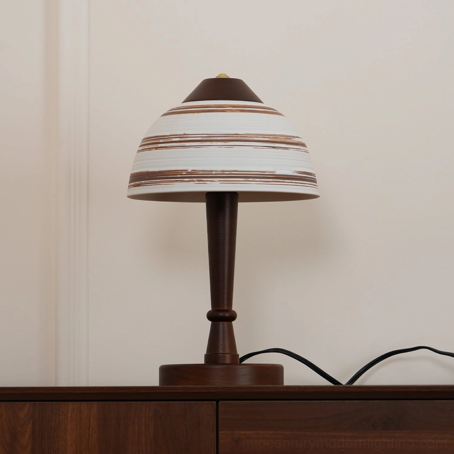 Athena table lamp front side view on wooden console table showing black power cord and ceramic shade striping
