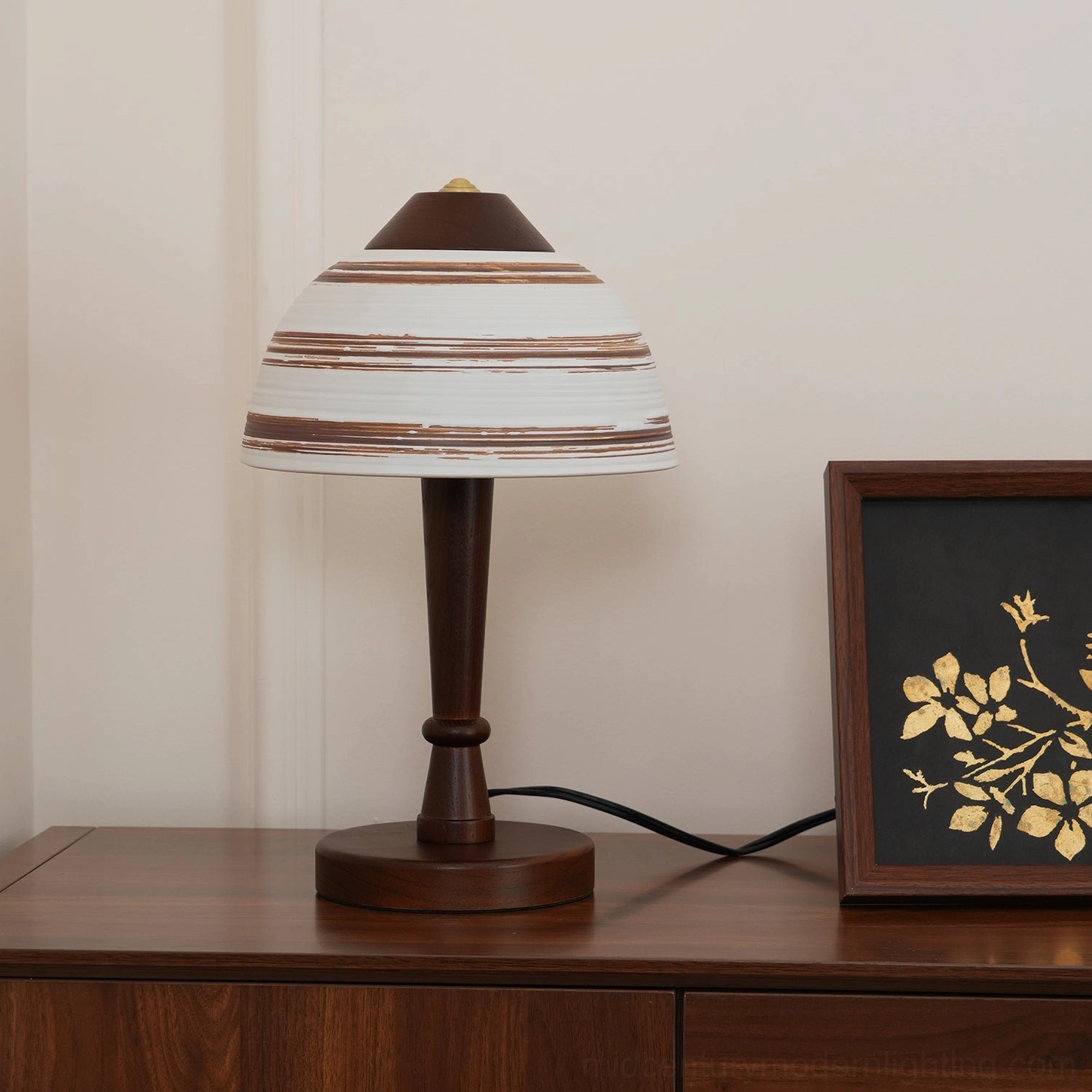 Athena mid-century table lamp three-quarter side view on wooden console with gold floral framed art and turned base