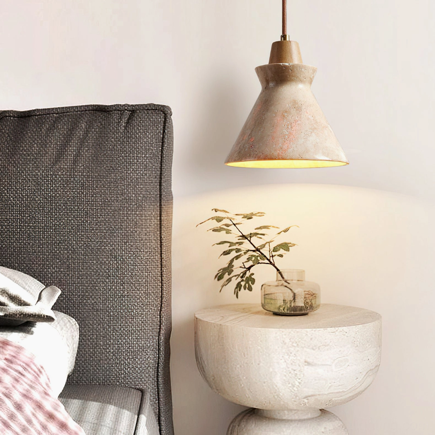 Close-up side view of Athena travertine pendant light with warm ambient glow near bedside table