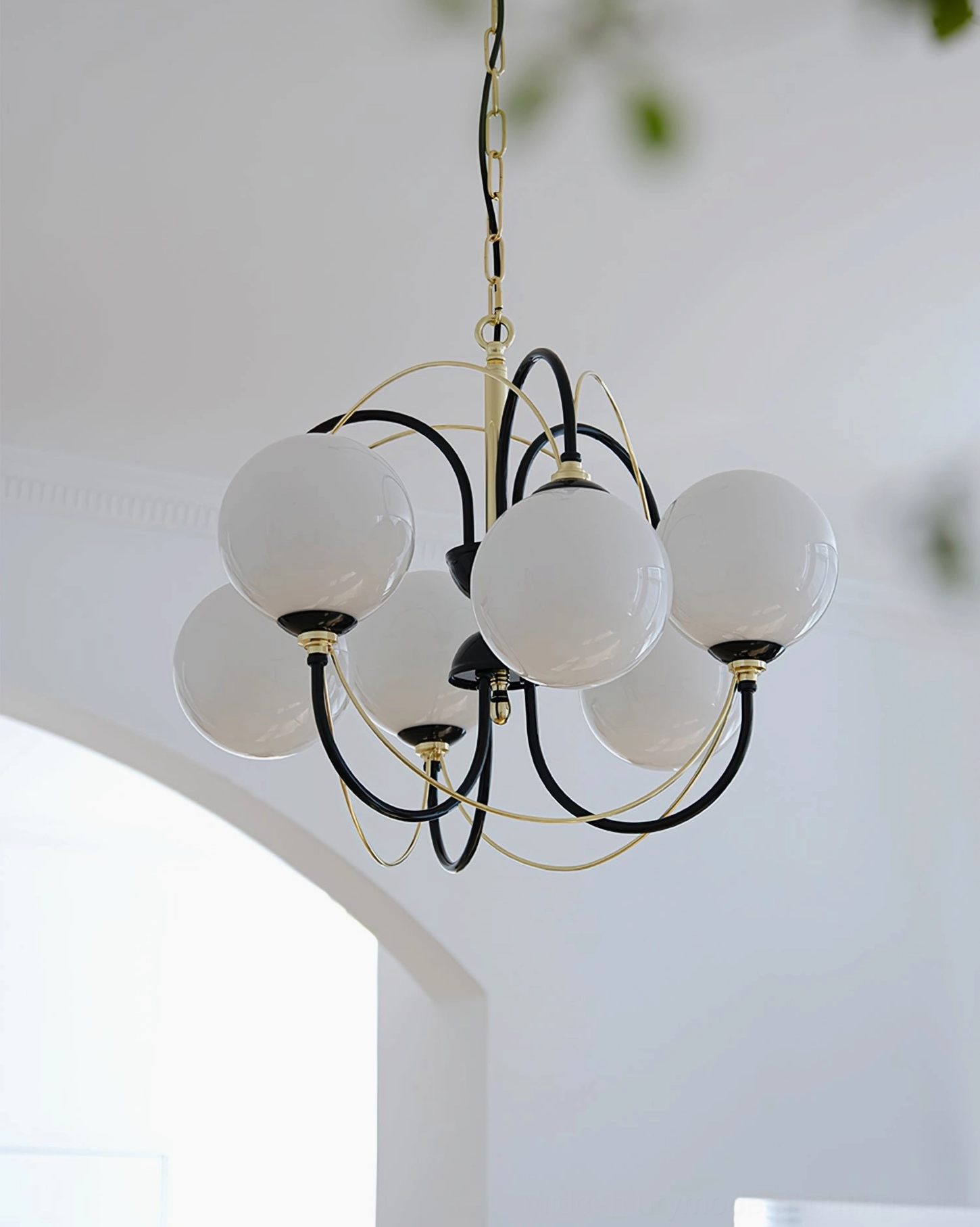 Three-quarter side view of Atomic Orbit six-globe chandelier in bright home hallway with black-gold metal frame