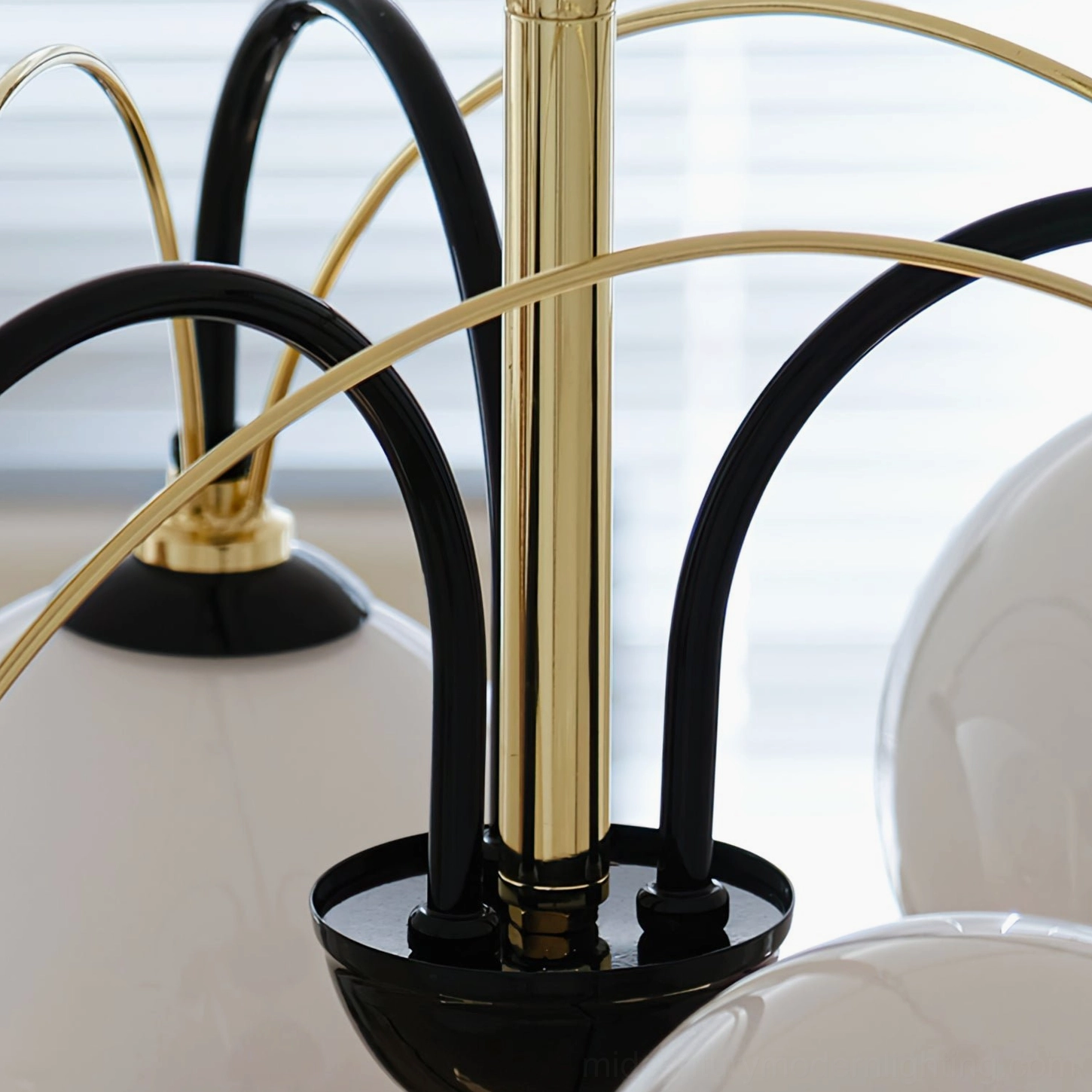 Detailed side close-up of Atomic Orbit chandelier curved black and gold metal arms against window background