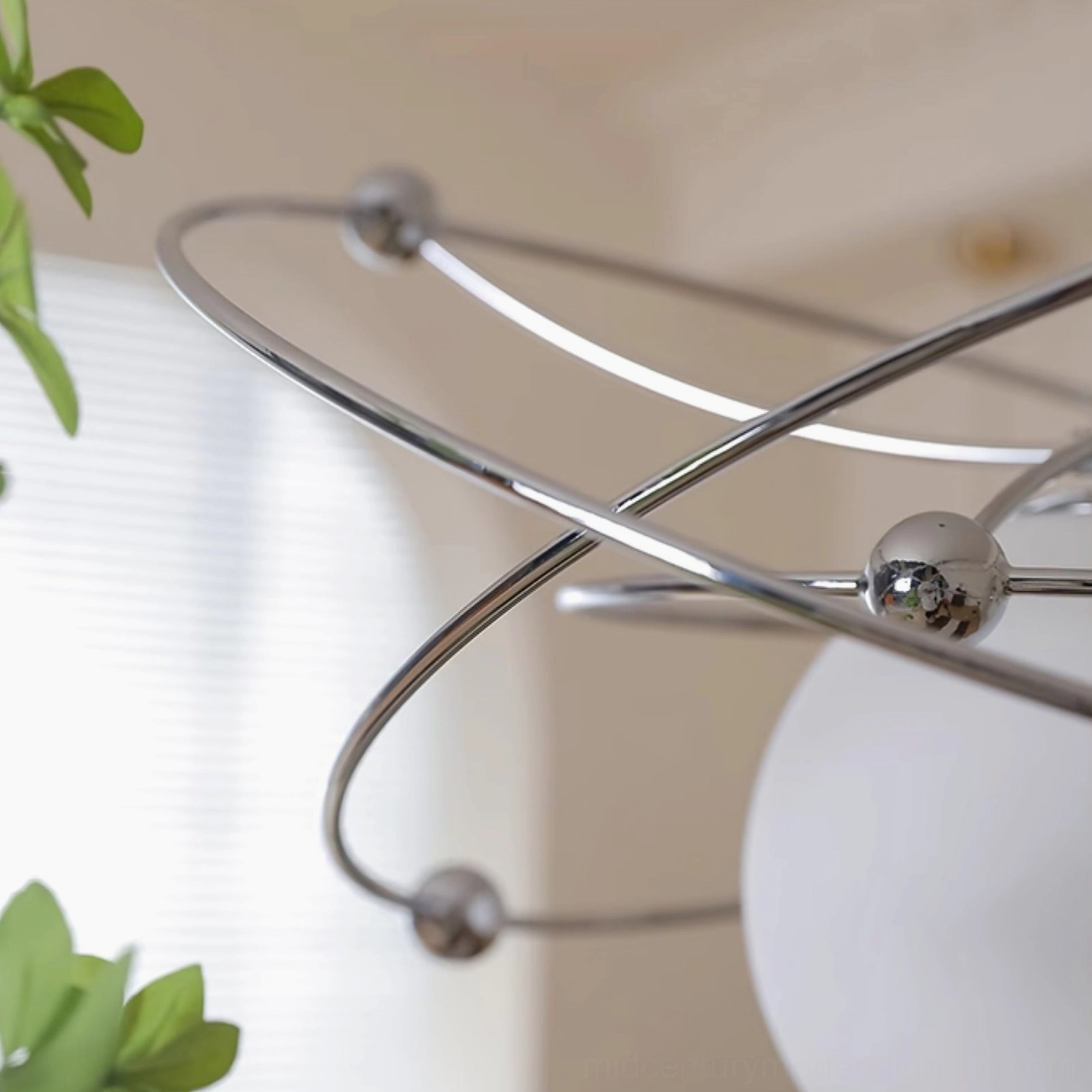 Close-up detail of polished chrome orbital rings and metal spheres of mid-century pendant light